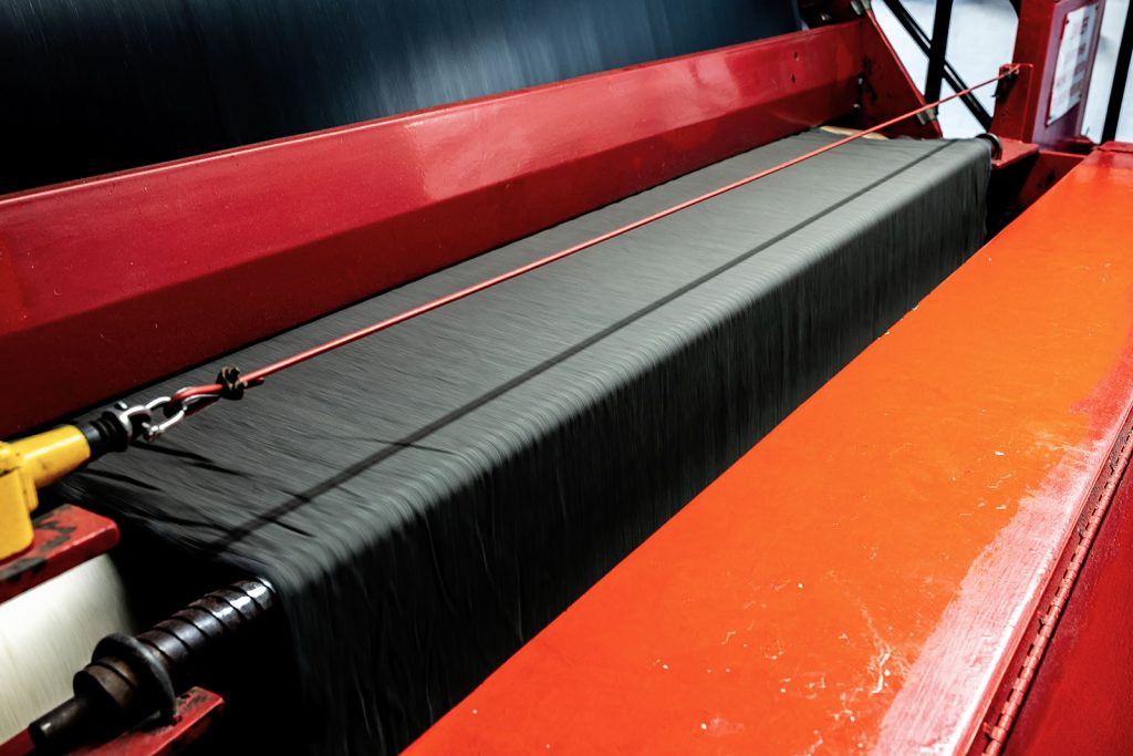 Black wool cloth running over a roller on the scouring machine