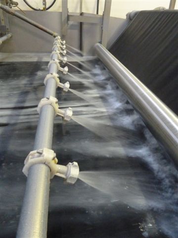 Spray nozzles applying a HALO REPEL chemical finish to wool cloth on the treatment machine