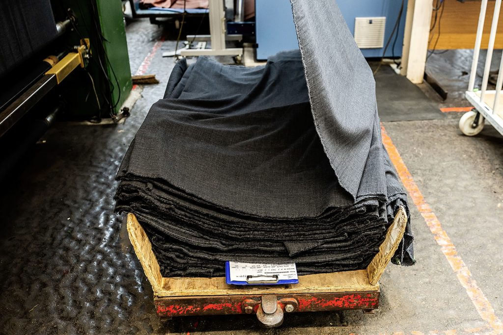 Folded grey and black cloth stacked on a trolley with a clipboard