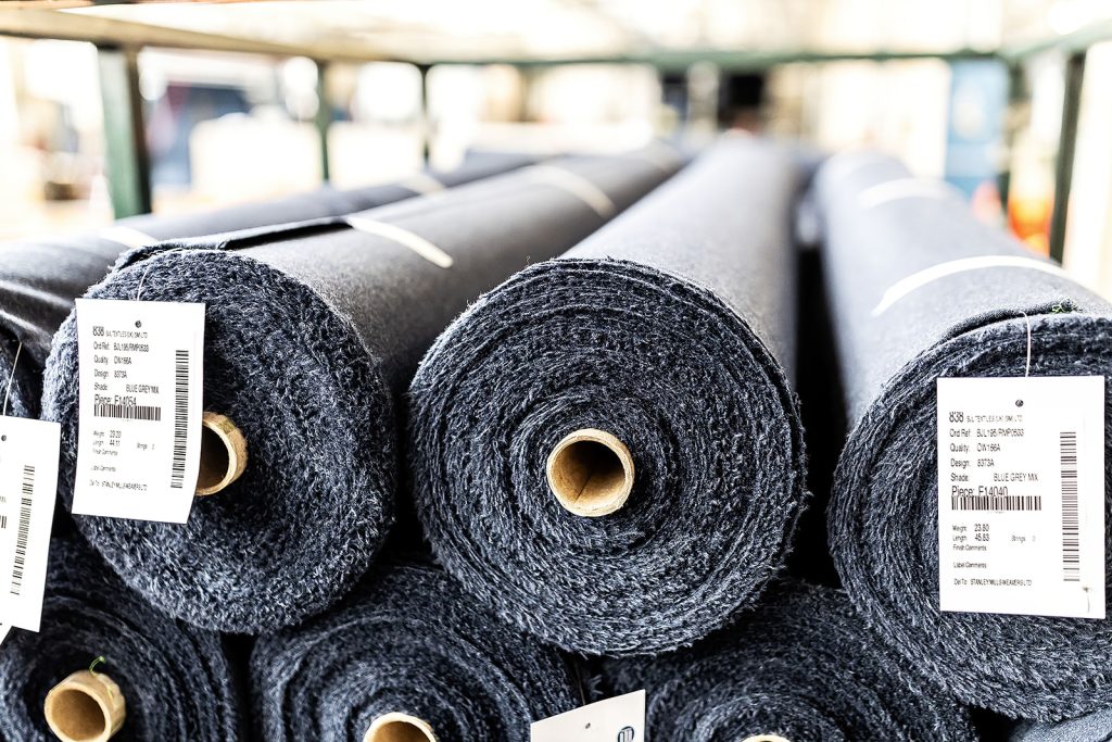 Rolled blue-grey wool cloth pieces with reference tags stored ready for batch decating
