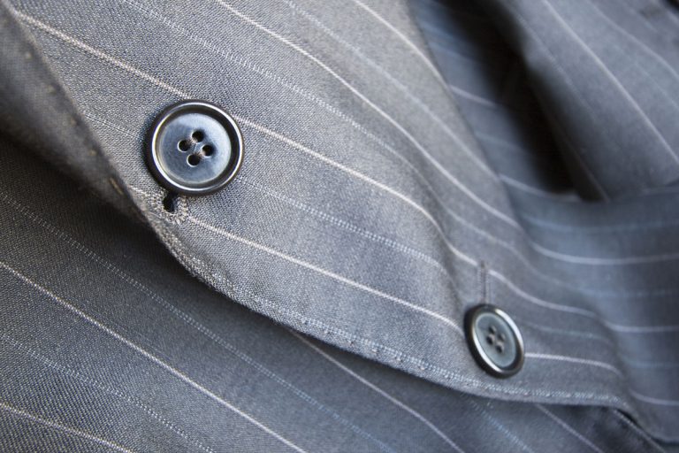 Close-up of buttons and buttonhole on a grey pinstripe suit jacket