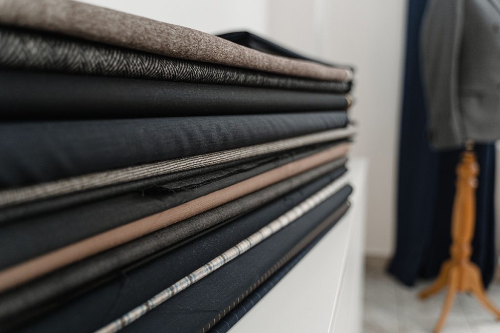 Stack of folded suiting cloth lengths in a range of patterns and colours