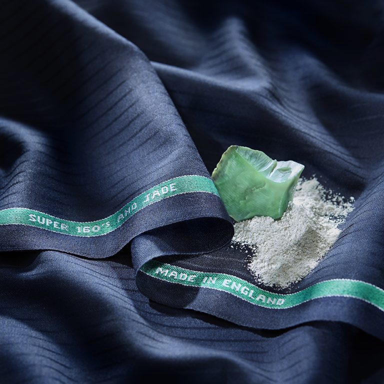 Navy wool cloth with a jade stone and powder beside its 'Super 160's and Jade' selvedge