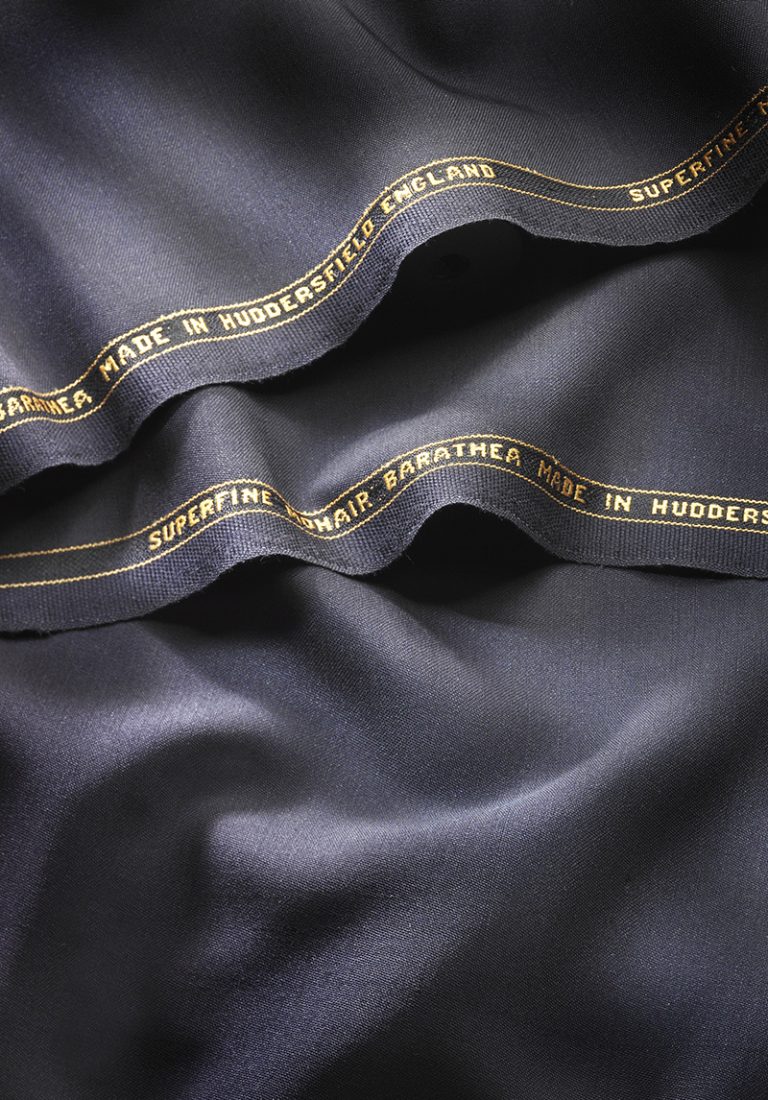 Close-up of navy superfine mohair barathea cloth with a gold Huddersfield selvedge