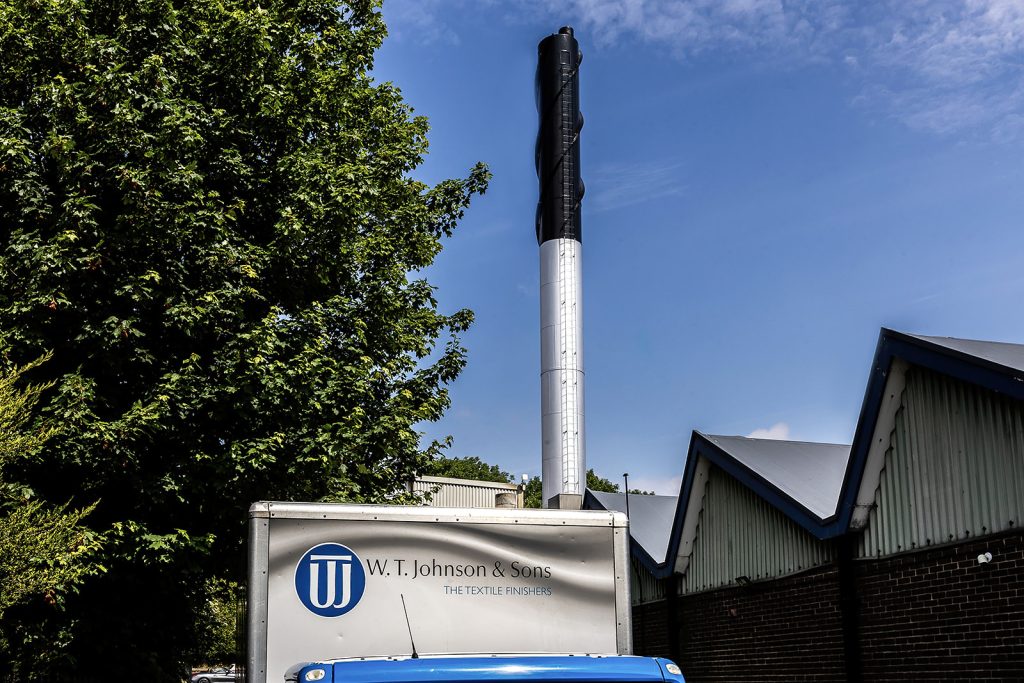 W.T. Johnson & Sons branded van parked outside the mill with its chimney behind